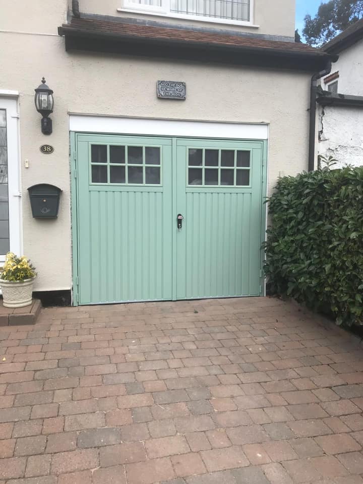 pale green side hined garage door instlled on pale pebble dash house